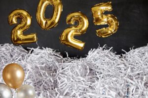 image of gold balloons that say "2025" and a pile of shredded paper