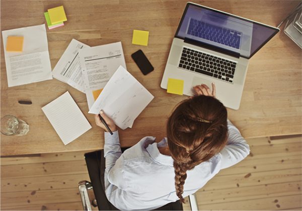 Person on a laptop holding documents